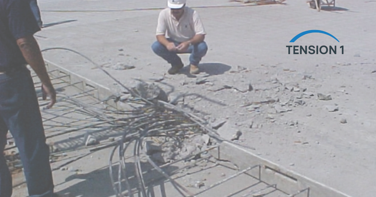 A construction site worker inspecting exposed and damaged steel tendons within a post tension slab for emergency repair.